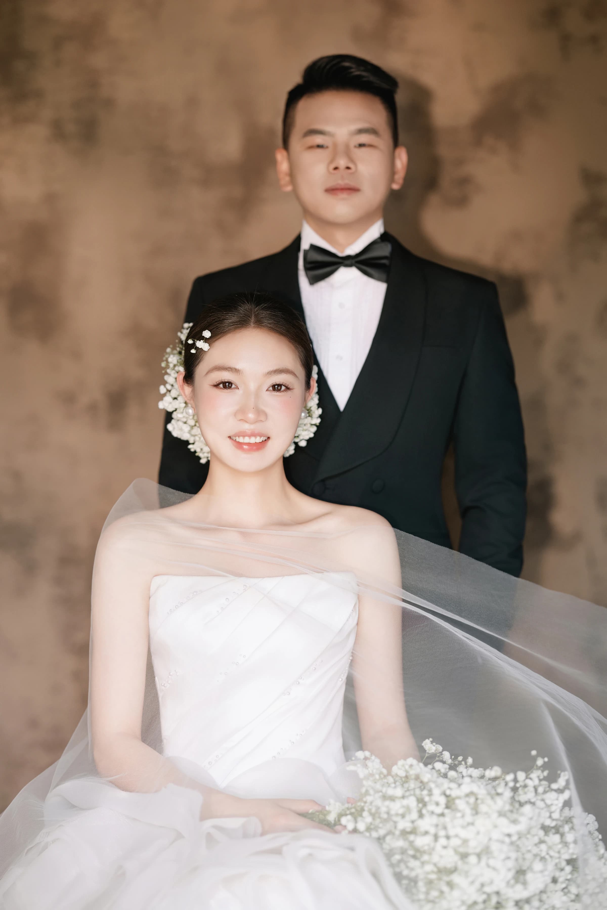 孔伟民与温守盼在暖色背景前的正式肖像