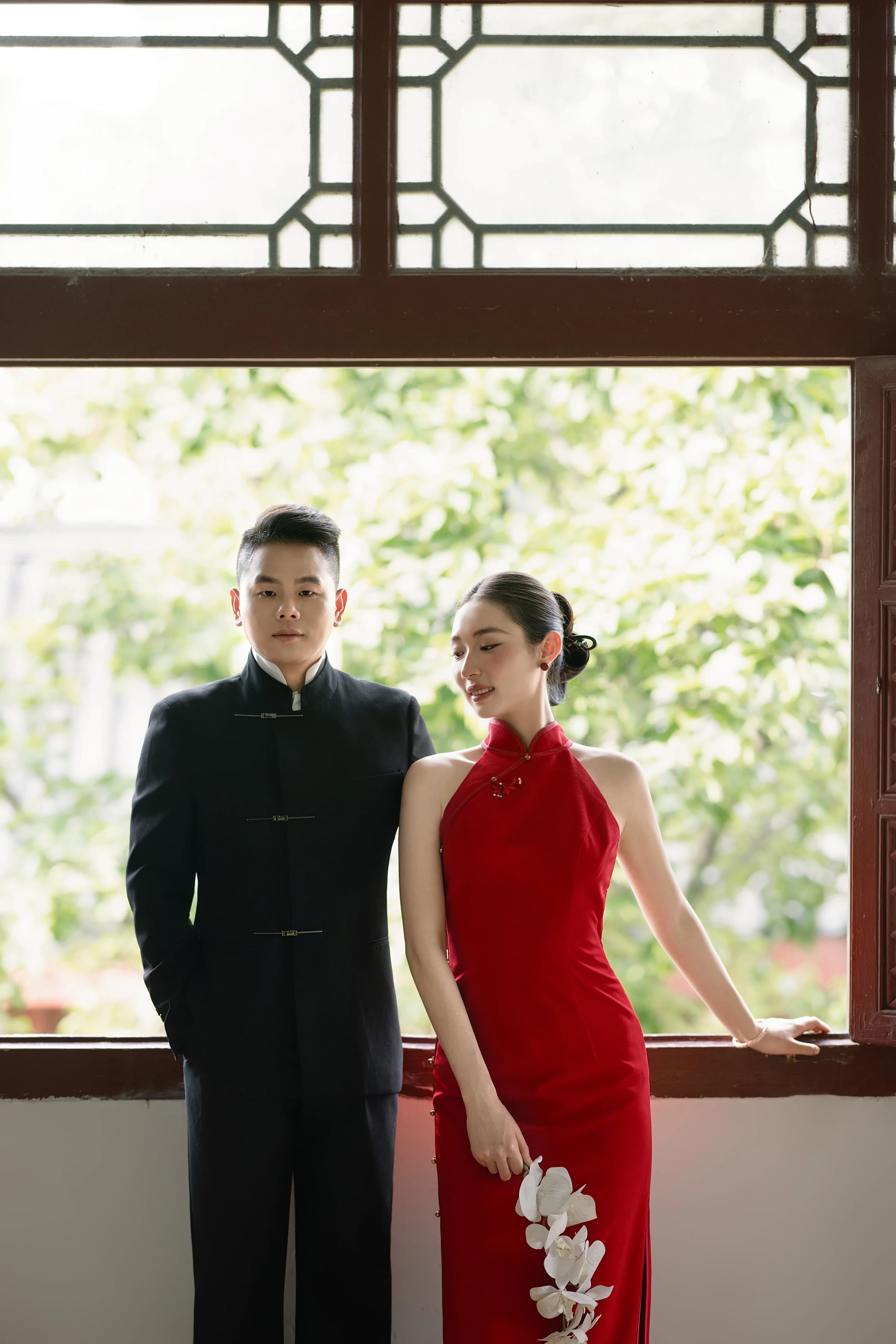 身着中式礼服的孔伟民与温守盼站在窗边